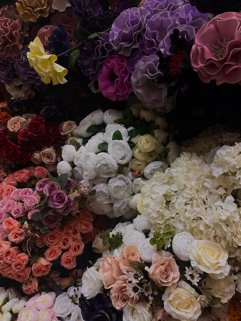 A variety of fresh floral arrangements featuring roses, hydrangeas, and lisianthus in soft pinks, whites, and creams, with some purple and yellow accents. The flowers are densely packed, showcasing th